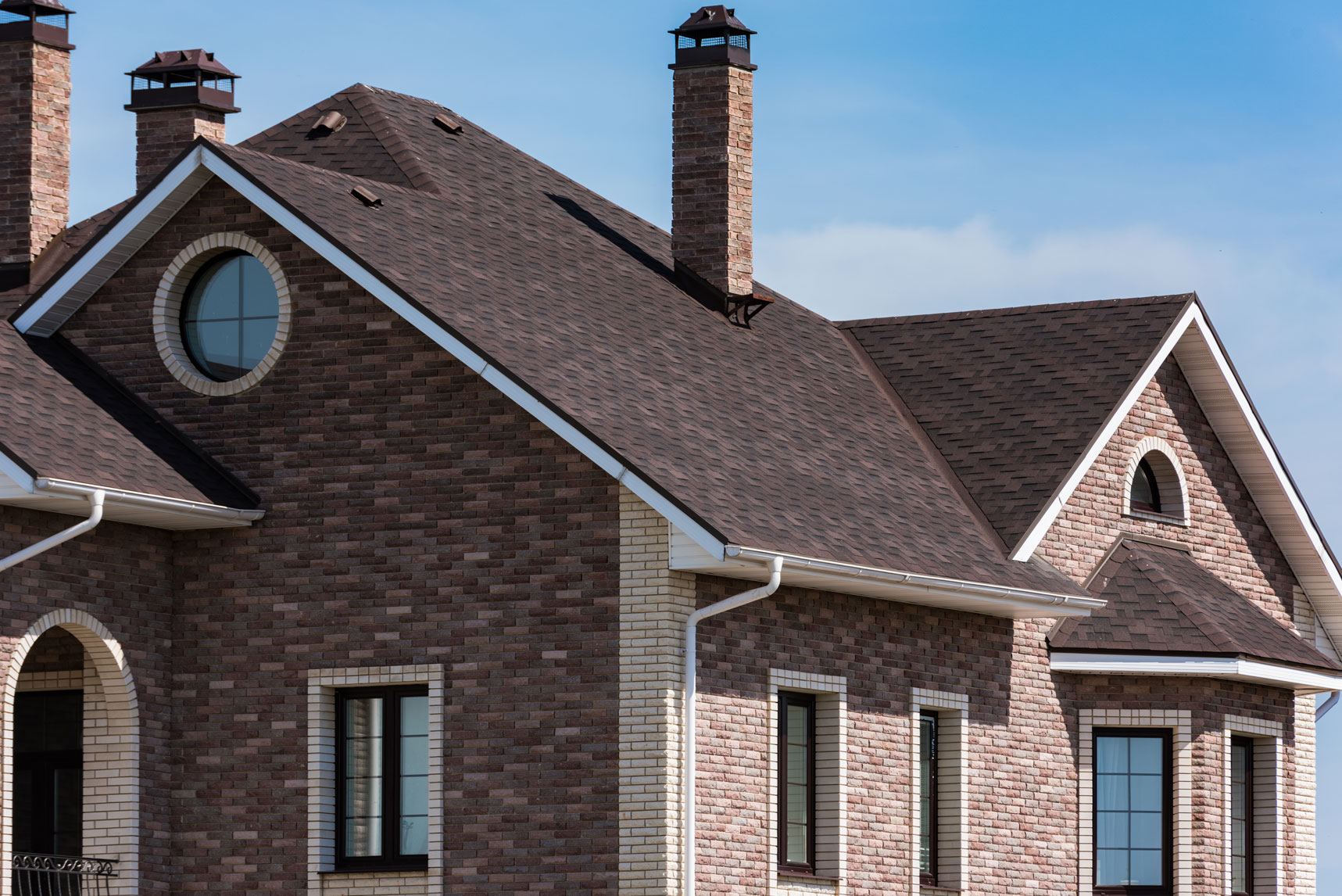 New roof on a brick home with multiple gables and chimneys